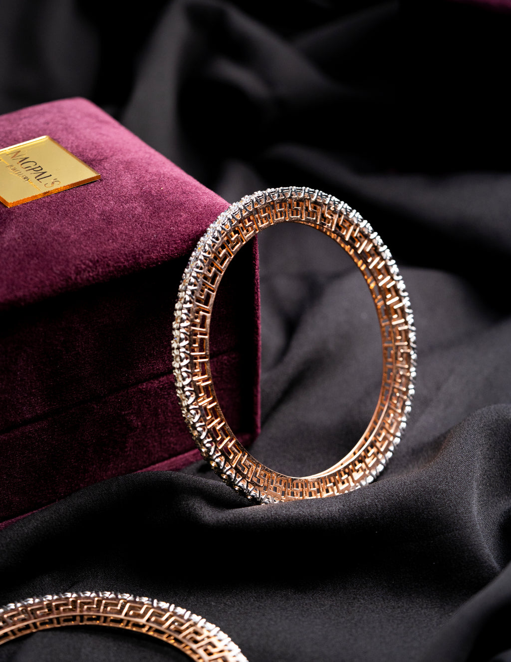 Gold Diamond bangles on a dark fabric background with a purple box in the background