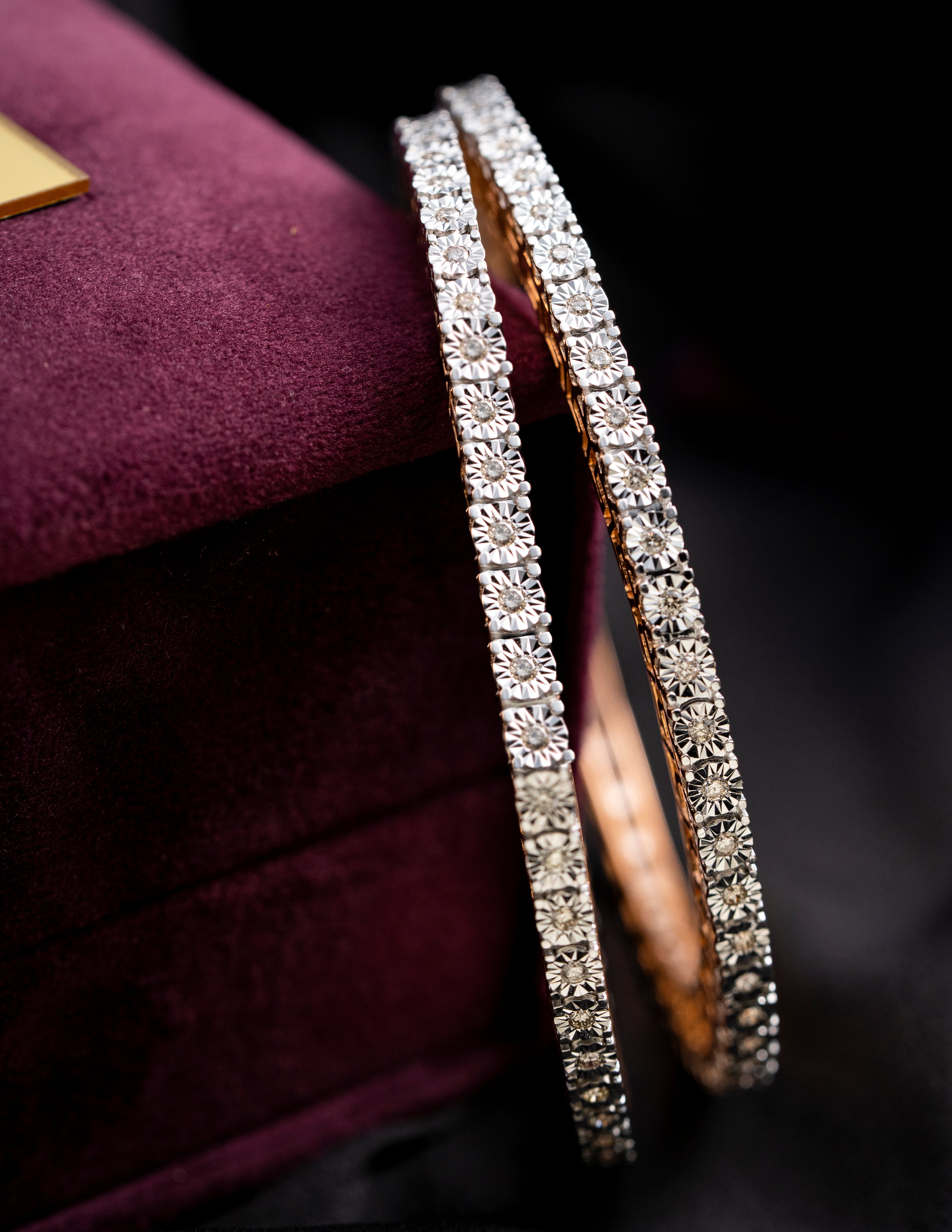 Pair of diamond-studded bangles on a dark background