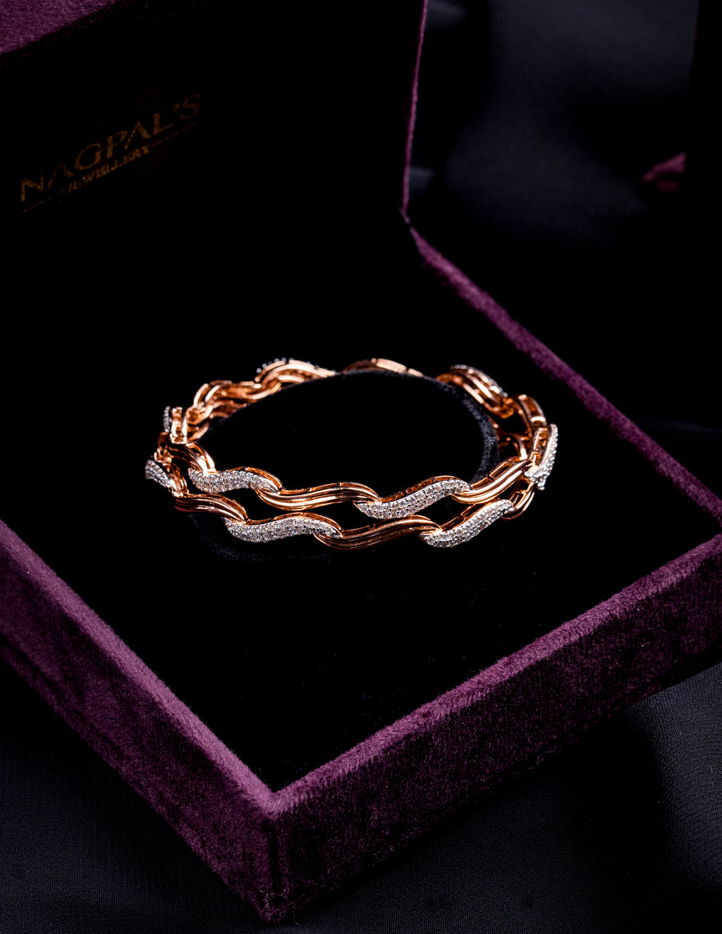 Rose gold bangles with diamonds on a purple velvet box