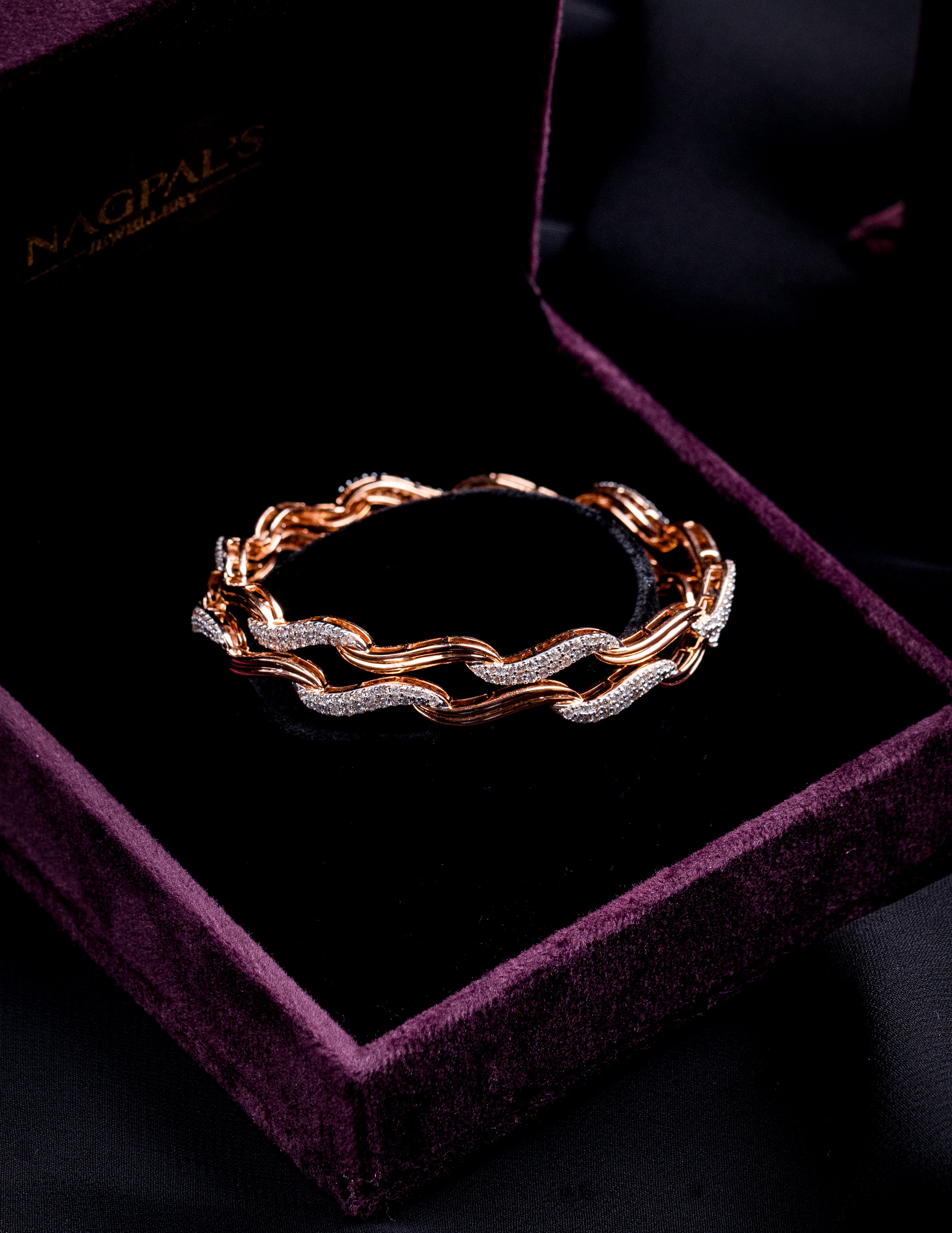 Rose gold bangles with diamonds on a purple velvet box